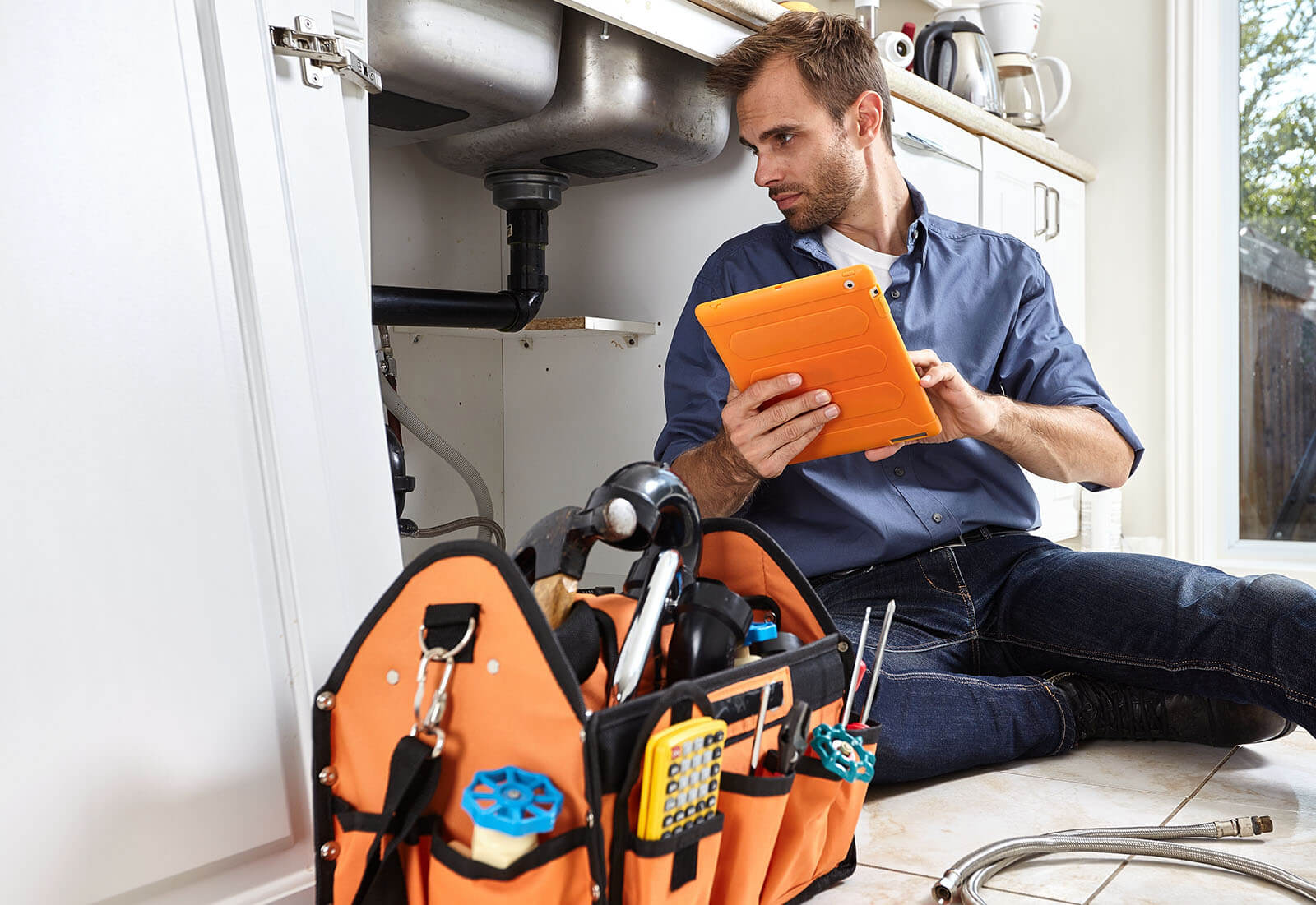 A contractor reviewing the job details on an iPad while completing a repair